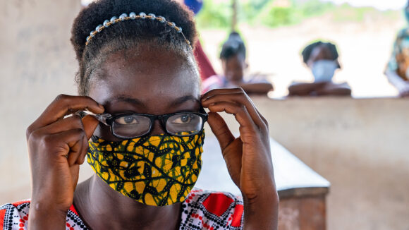 A close-up of Patience wearing glasses and a face mask.